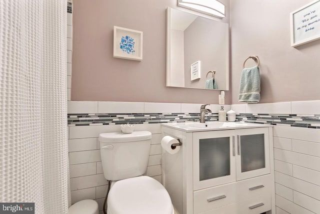 bathroom with tile walls, a shower with curtain, vanity, and toilet