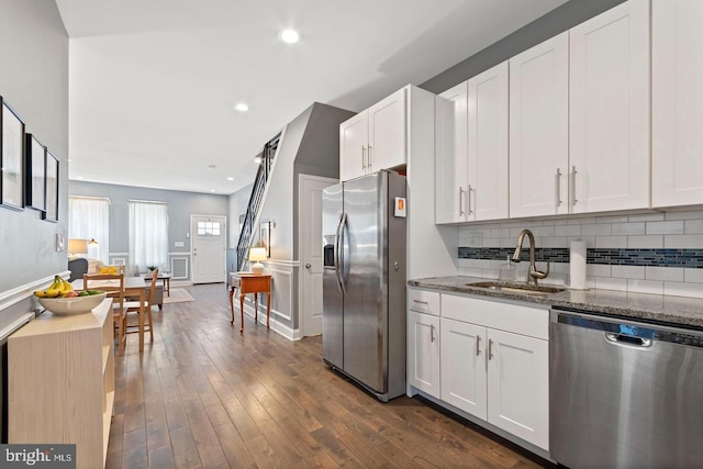 kitchen with sink, stainless steel appliances, dark stone countertops, and white cabinetry