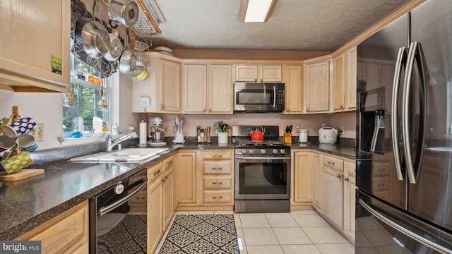 kitchen featuring stainless steel appliances, a textured ceiling, light brown cabinets, and light tile patterned floors