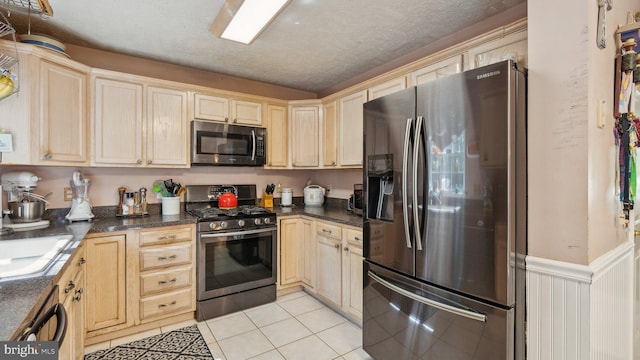 kitchen with light brown cabinetry, sink, a textured ceiling, light tile patterned floors, and appliances with stainless steel finishes