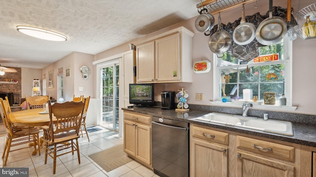 kitchen featuring a stone fireplace, black dishwasher, sink, and light brown cabinets