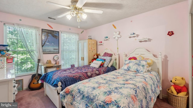 bedroom with ceiling fan, carpet flooring, and a textured ceiling