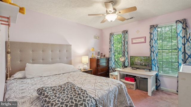 bedroom with ceiling fan, carpet flooring, and a textured ceiling