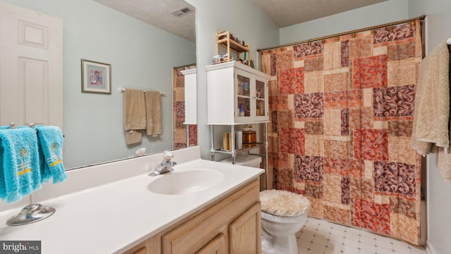 bathroom with vanity, toilet, a shower with shower curtain, and a textured ceiling