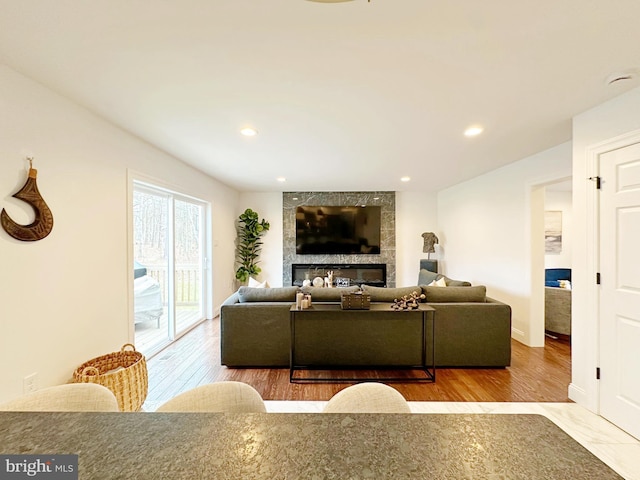 living room with a tile fireplace and light hardwood / wood-style floors