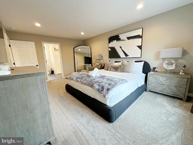 bedroom featuring ensuite bath and light carpet