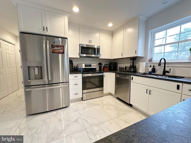 kitchen featuring stainless steel appliances, white cabinetry, and sink