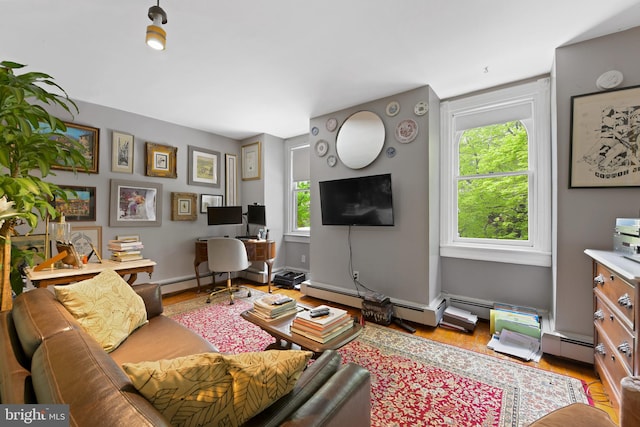living room with a baseboard heating unit, wood finished floors, and a healthy amount of sunlight