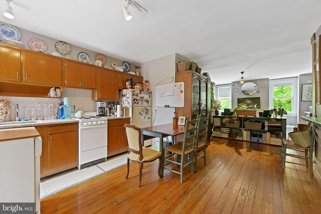 kitchen featuring light countertops, white appliances, a sink, and light wood-style floors