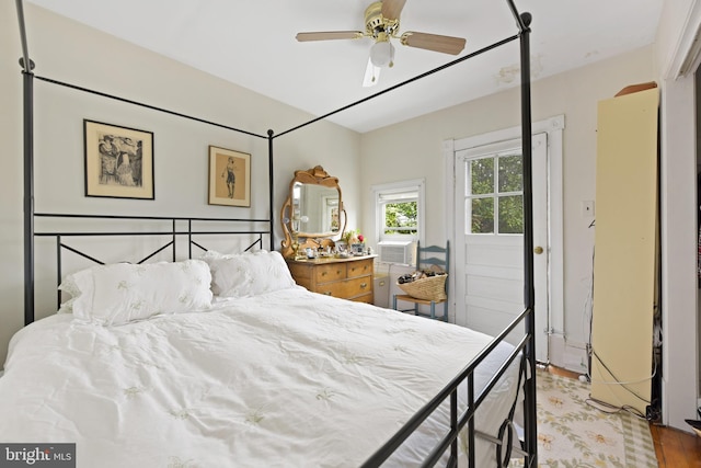 bedroom with a ceiling fan, wood finished floors, and cooling unit