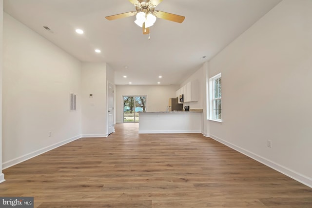 unfurnished living room featuring ceiling fan and hardwood / wood-style floors