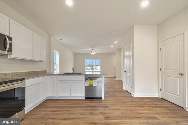 kitchen with kitchen peninsula, white cabinets, appliances with stainless steel finishes, ceiling fan, and sink