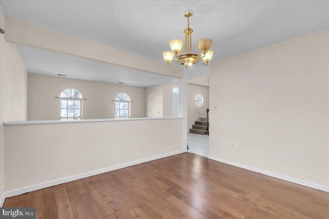 spare room with hardwood / wood-style floors and a notable chandelier