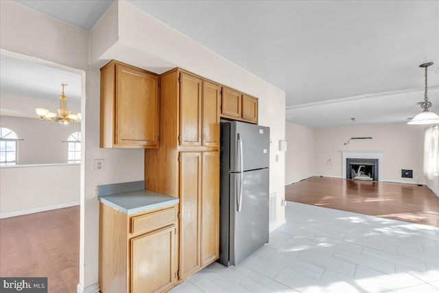 kitchen featuring decorative light fixtures, stainless steel fridge, a chandelier, and light wood-type flooring