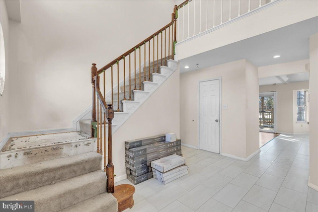 stairway with tile patterned floors and a high ceiling