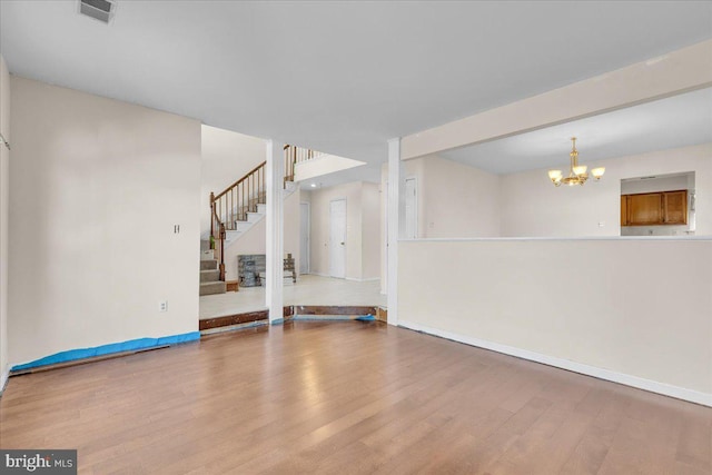 empty room with hardwood / wood-style flooring and a chandelier