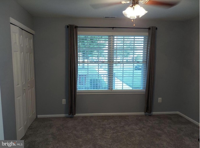 spare room featuring ceiling fan and dark carpet