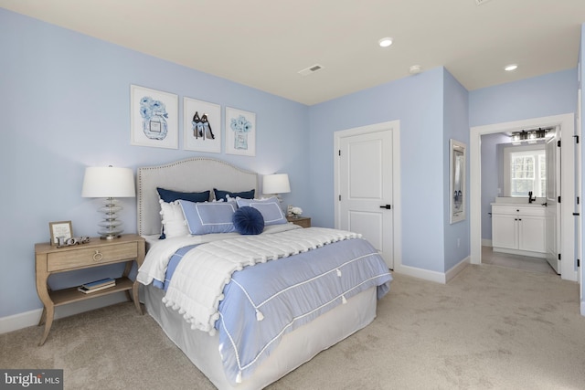 bedroom featuring light colored carpet and connected bathroom