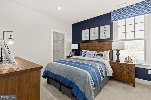 bedroom with a closet, light carpet, and a spacious closet