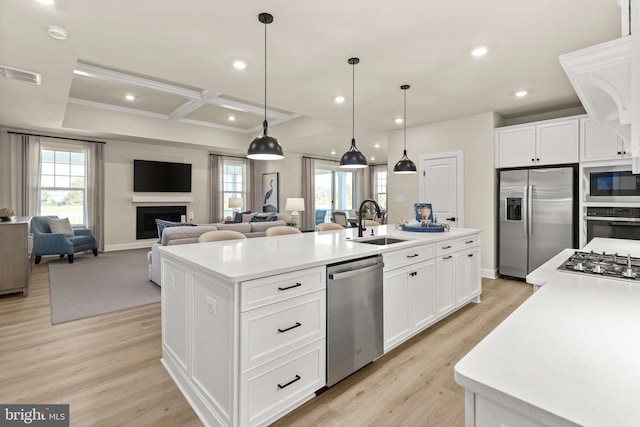 kitchen featuring appliances with stainless steel finishes, white cabinets, sink, and a center island with sink