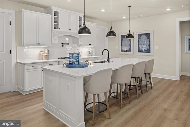 kitchen with white cabinets, a kitchen island with sink, tasteful backsplash, and sink