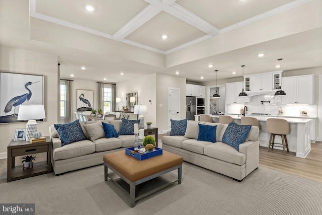 living room featuring light wood-type flooring, crown molding, beamed ceiling, and sink