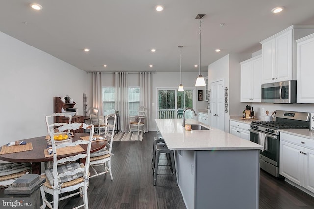 kitchen featuring appliances with stainless steel finishes, white cabinets, a center island with sink, and sink