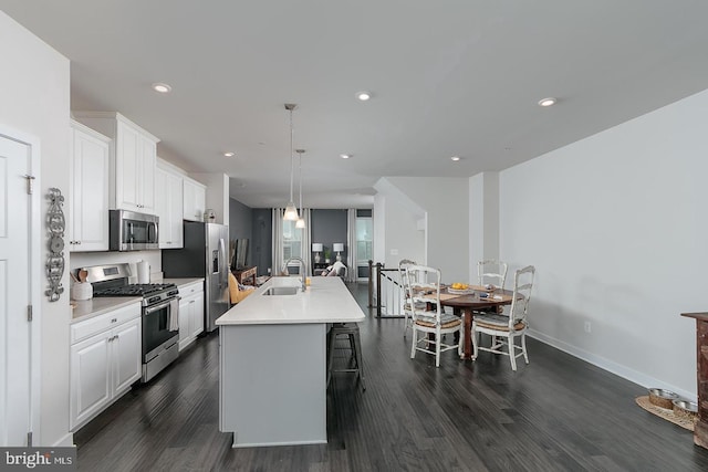 kitchen with stainless steel appliances, white cabinetry, an island with sink, and sink