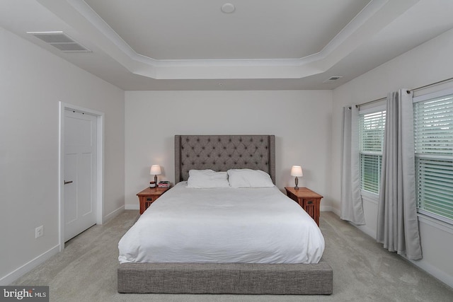 bedroom with ornamental molding, light colored carpet, and a tray ceiling