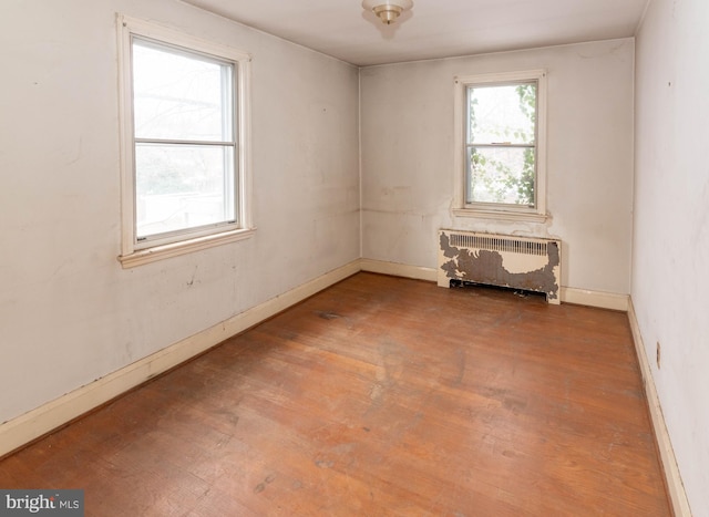 empty room with radiator heating unit and hardwood / wood-style floors