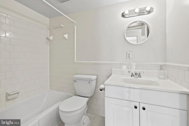 full bathroom with toilet, tile walls, vanity, and tiled shower / bath combo