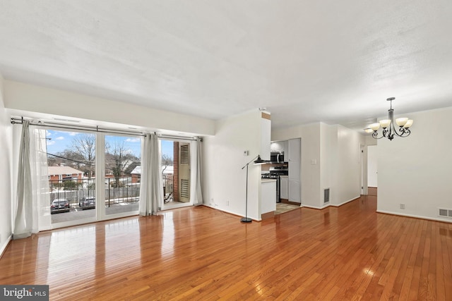 unfurnished living room with light hardwood / wood-style flooring and a notable chandelier