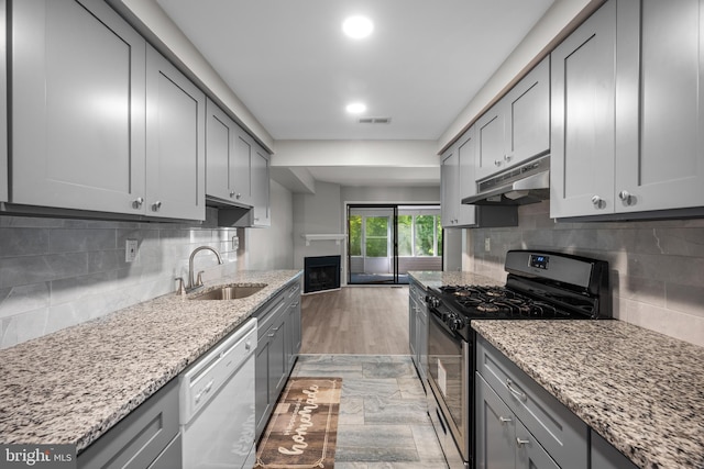 kitchen with backsplash, light stone countertops, dishwasher, and stainless steel range with gas cooktop