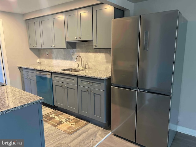 kitchen featuring light stone countertops, appliances with stainless steel finishes, gray cabinetry, and sink