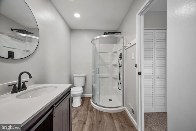 bathroom with toilet, wood-type flooring, vanity, and a shower with shower door