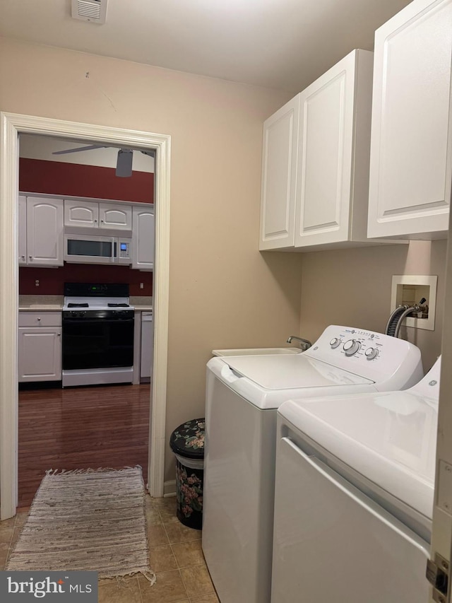 laundry room with washing machine and dryer, cabinets, and tile patterned flooring