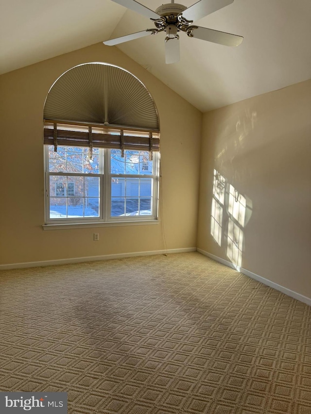 empty room featuring ceiling fan, vaulted ceiling, and light carpet