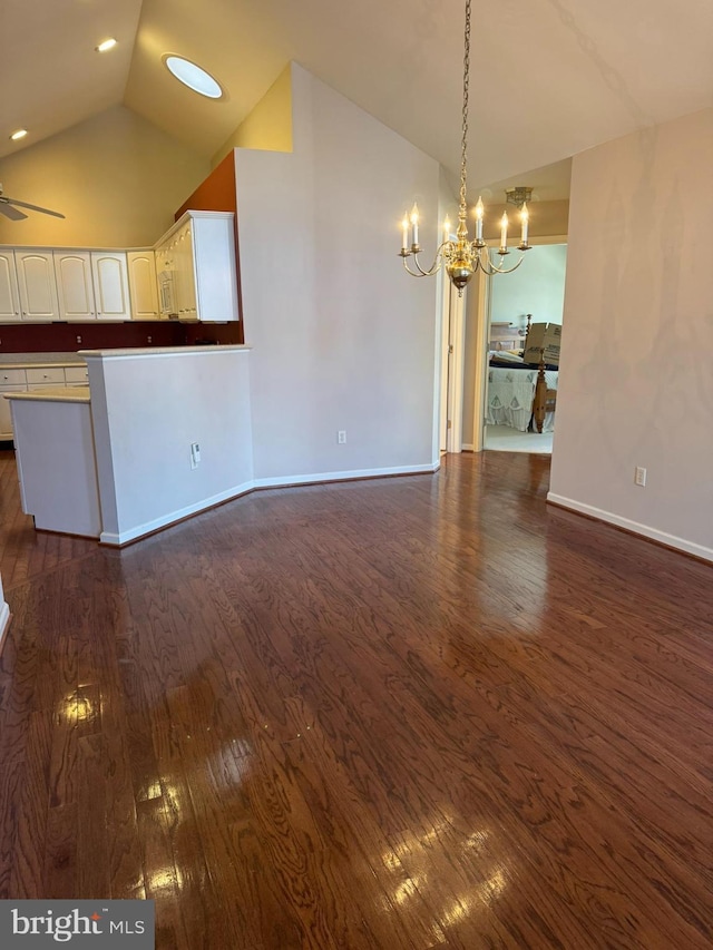 unfurnished living room with ceiling fan with notable chandelier, dark hardwood / wood-style floors, and lofted ceiling