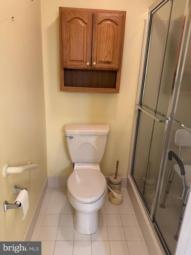 bathroom with toilet, tile patterned floors, and an enclosed shower