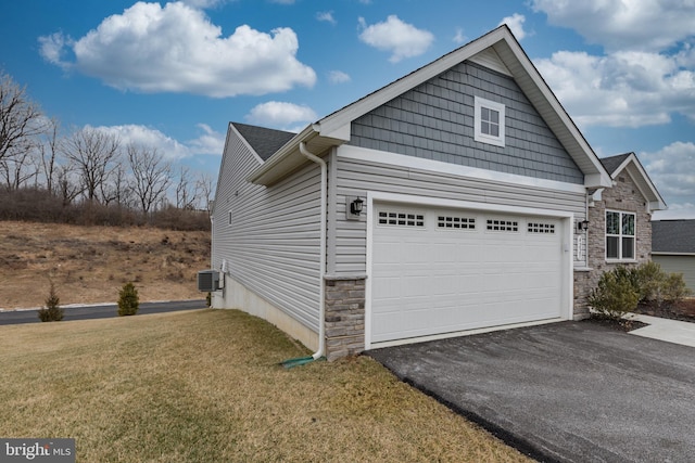 view of side of home featuring a garage, cooling unit, and a yard