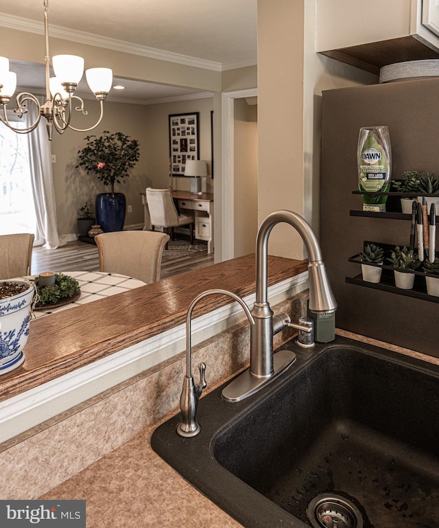 kitchen with crown molding, pendant lighting, sink, and a notable chandelier