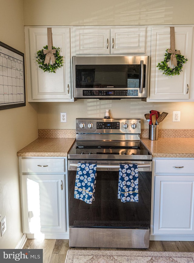 kitchen featuring white cabinetry, appliances with stainless steel finishes, and light hardwood / wood-style floors