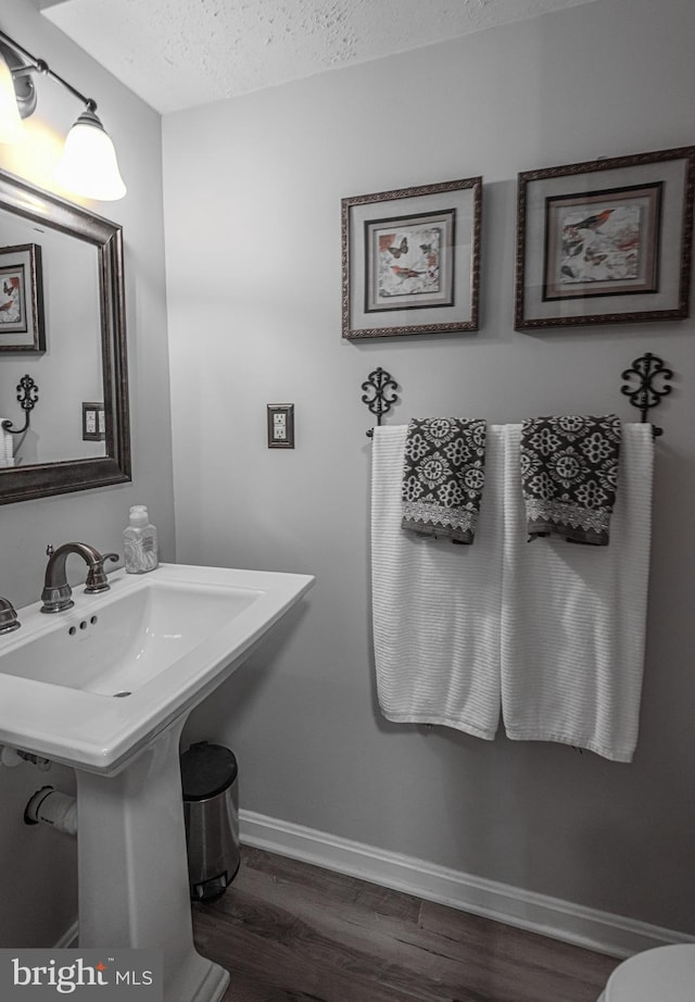 bathroom featuring wood-type flooring and a textured ceiling