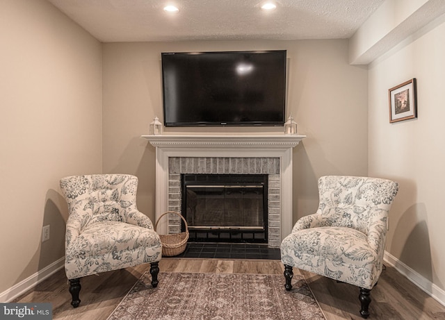 sitting room featuring dark hardwood / wood-style floors, a textured ceiling, and a fireplace