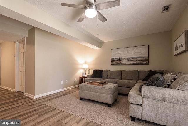 living room featuring ceiling fan, hardwood / wood-style flooring, and a textured ceiling