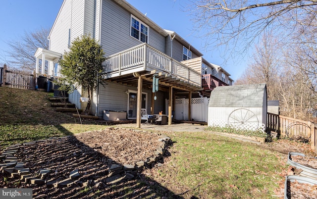 back of house featuring a wooden deck, a patio area, a shed, and a lawn