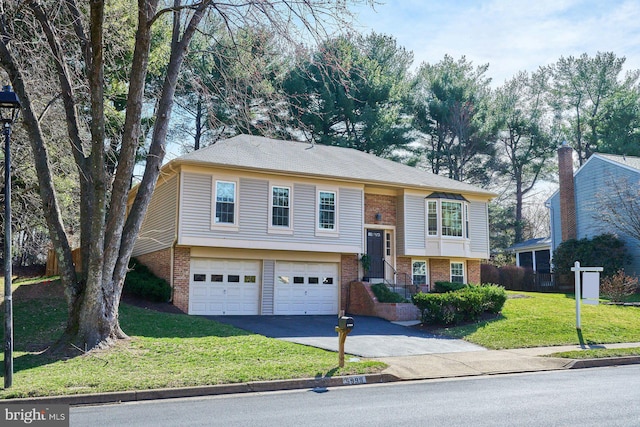 bi-level home featuring a front lawn, an attached garage, brick siding, and aphalt driveway