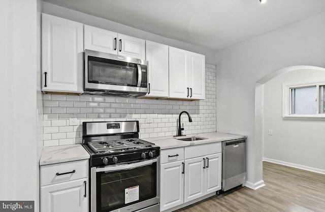 kitchen with stainless steel appliances, white cabinetry, and sink