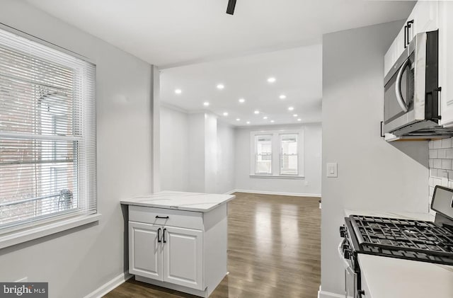 kitchen featuring appliances with stainless steel finishes, dark wood-type flooring, white cabinets, and light stone counters