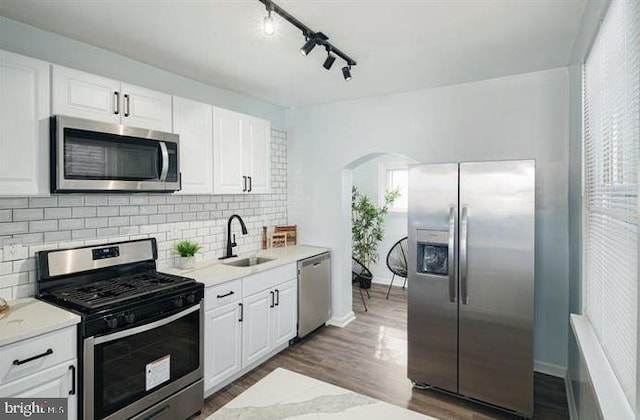 kitchen featuring appliances with stainless steel finishes, dark wood-type flooring, sink, white cabinetry, and backsplash